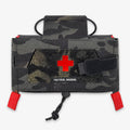 Rettungsgriff MOLLE-Verbandtasche in schwarzem Multicam, Frontalansicht mit rotem Kreuz und Zugband