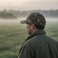 Jäger mit Camo Jagd-Cap am nebligen Feld im Morgengrauen