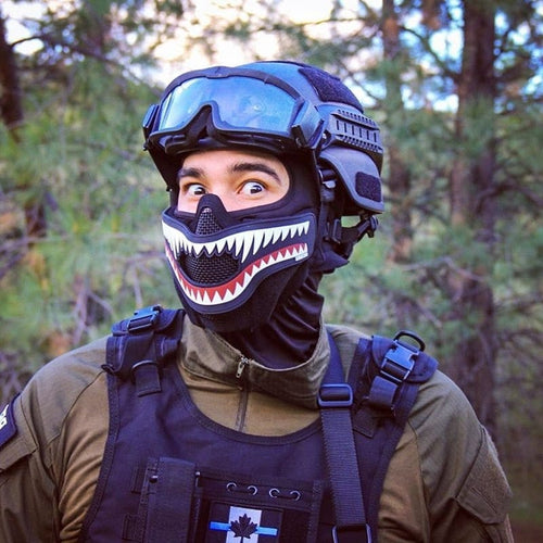 StrikeGuard Maske in Schwarz mit Hai-Zähnen, Schütze mit Helm und Brille im Wald, Nahaufnahme