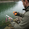 Uferfuchs Köderretter, Angler löst pinken Spinner vom Haken am Flussufer