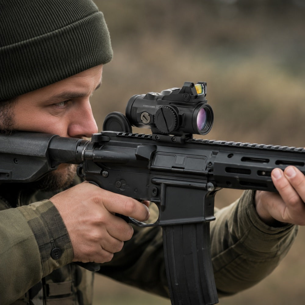 Prismenvisier mit Rotpunkt auf einem Gewehr im Anschlag, beide Augen offen