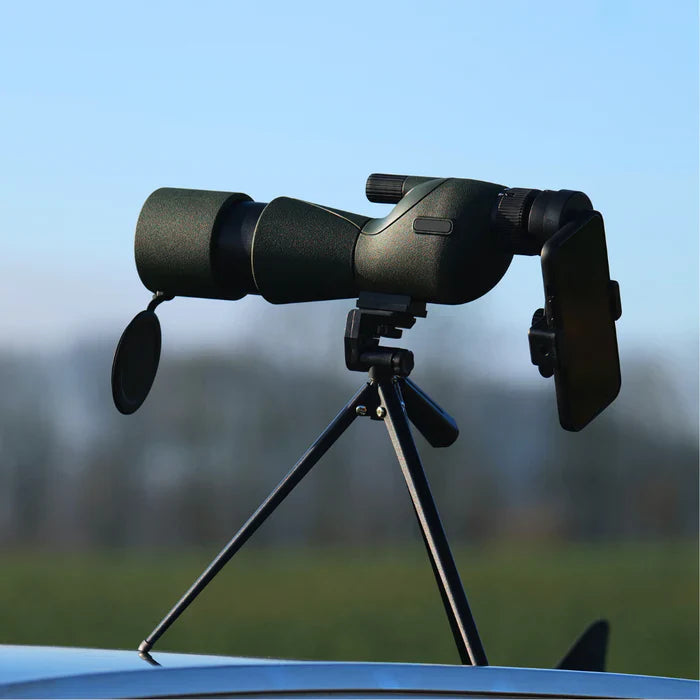 ZoomMeister Spektiv auf Mini-Stativ auf Autodach, Objektivdeckel hängt an der Linse, Feld im Hintergrund