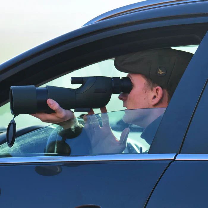 ZoomMeister Spektiv, Jäger mit Schiebermütze blickt aus dem offenen Autofenster hindurch