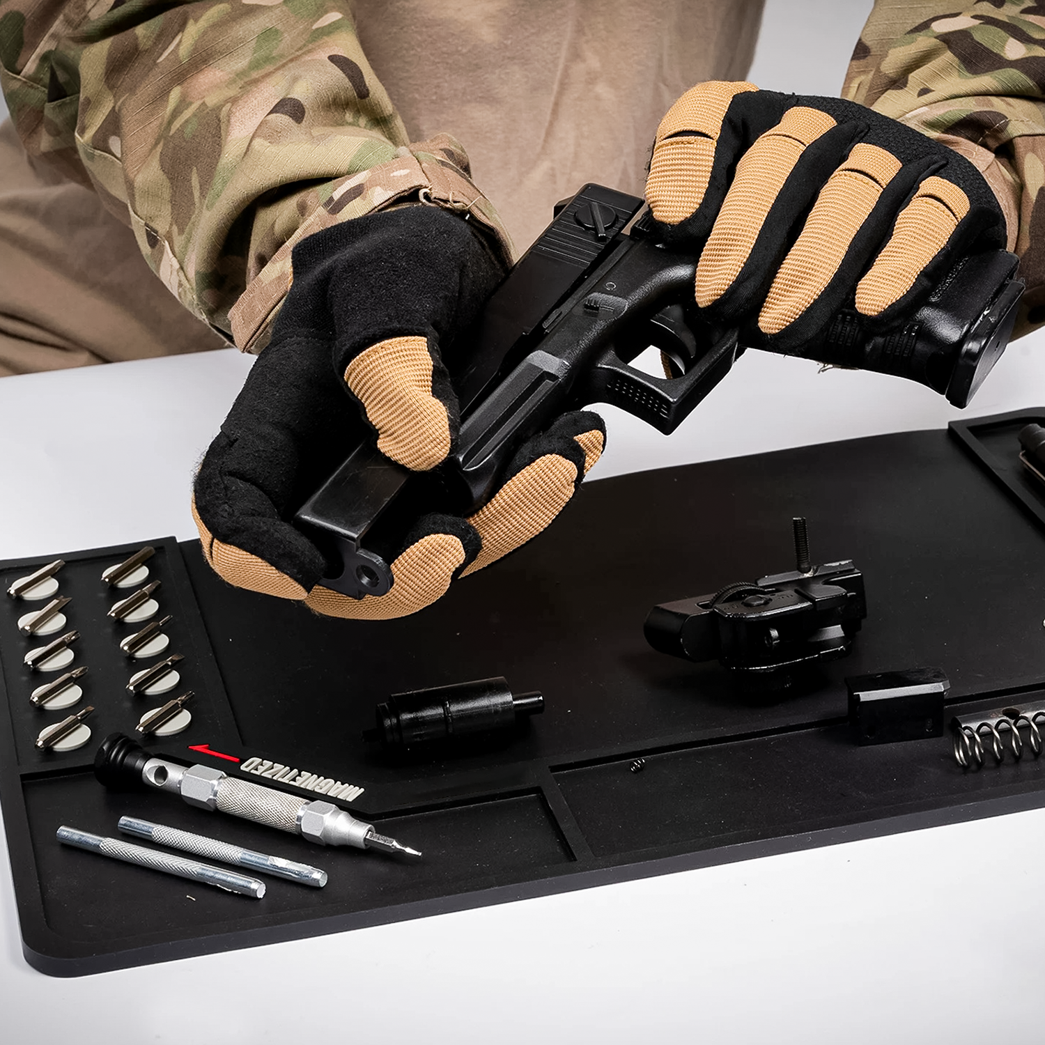 MagnetMat 360, Schuetze mit Tarnjacke und Handschuhen zerlegt Pistole ueber der Werkzeugmatte