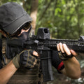 Airsoft-Spieler mit Leuchtpunktvisier auf einer M4 im Wald