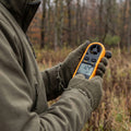 Jaeger prueft den Wind mit dem digitalen Windmesser am Waldrand